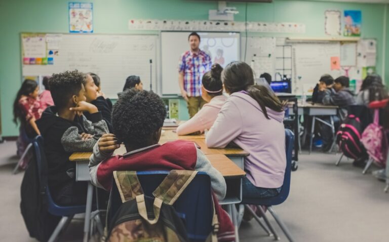 Salle de classe avec des élèves qui lèvent la main